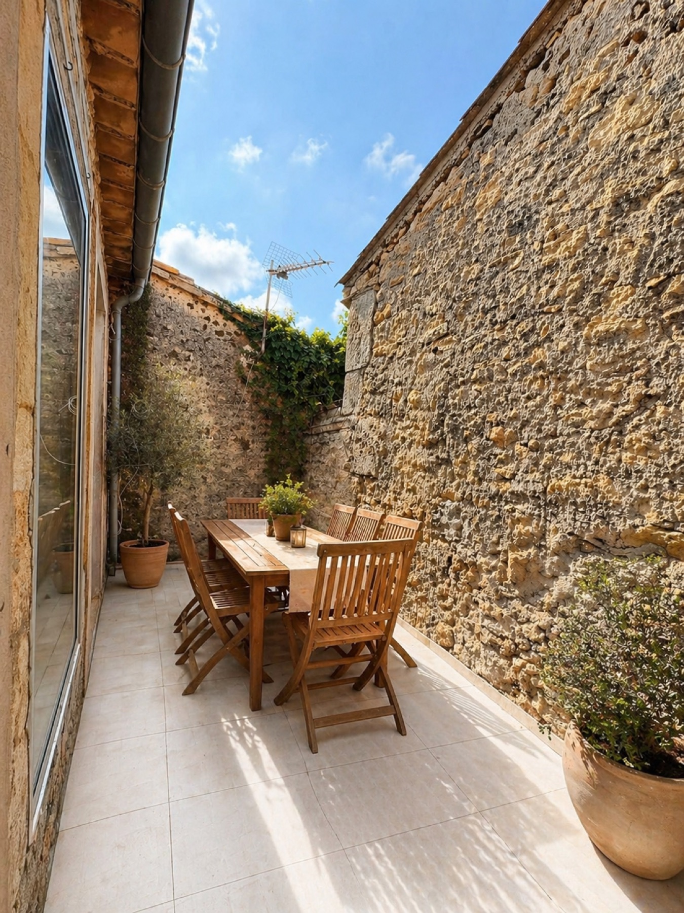Patio avec mur en pierre et table extérieure à Sérignan